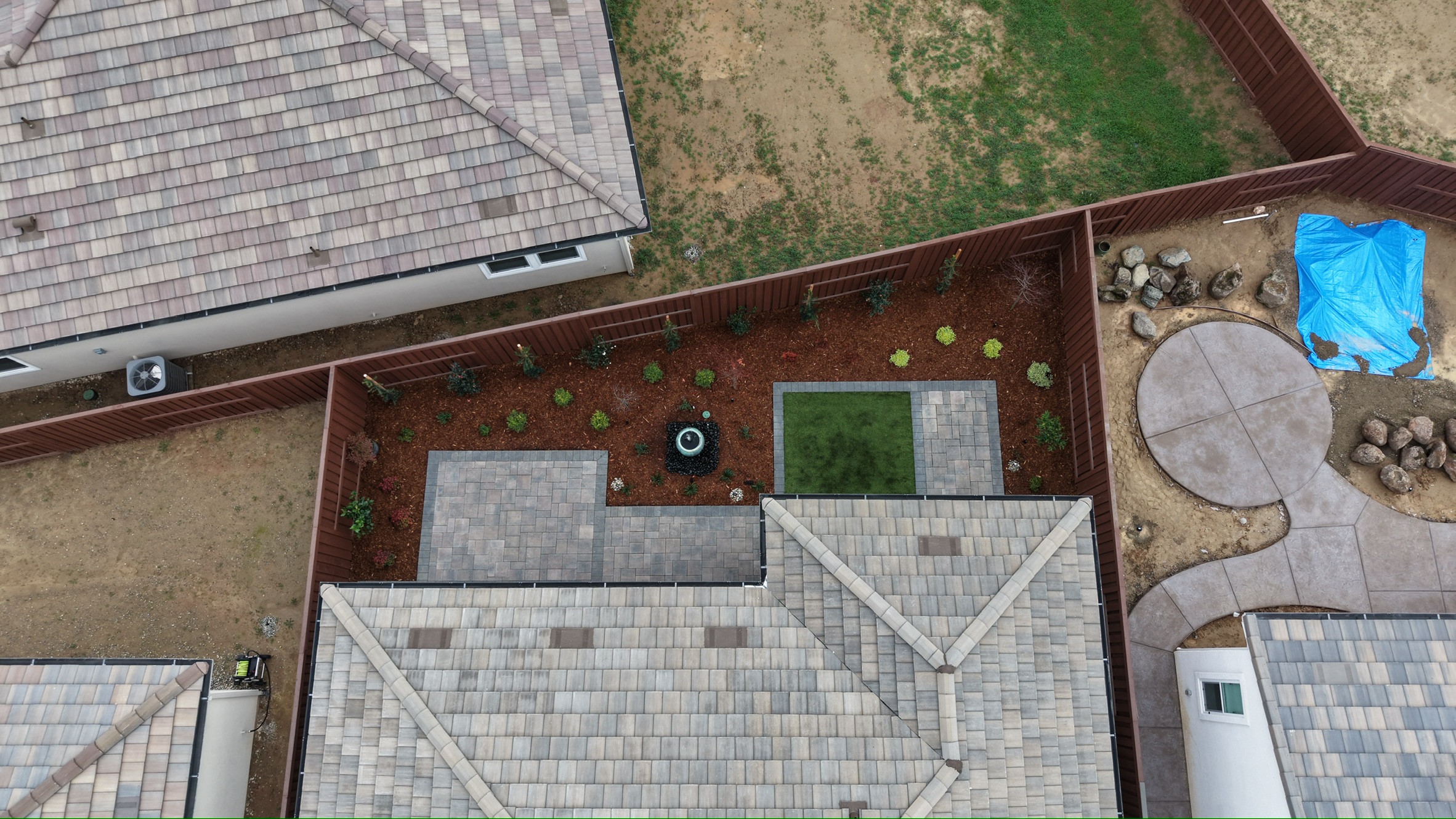 Overhead view of luxury estate grounds showing lush landscaping, terraced gardens, and a winding driveway